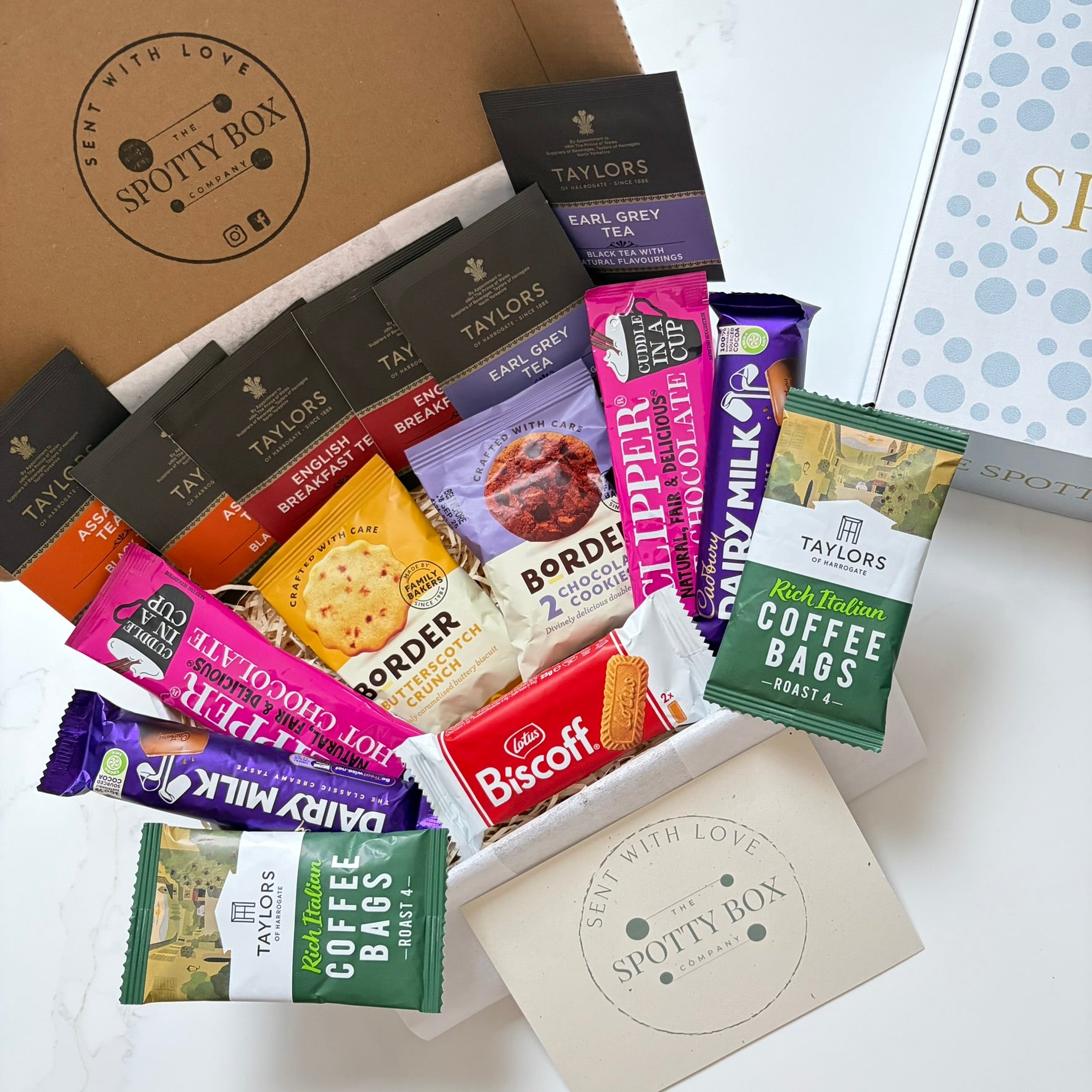 hot drink and biscuit gift hamper from the spotty box company containing taylors coffee sachets, taylors tea selection, border biscuits. cadbury dairy milk and clippers hot chocolate and a lotus biscoff biscuit. all presented in a tasteful 'spotty' box, ideal as a gift for tea and coffee lovers