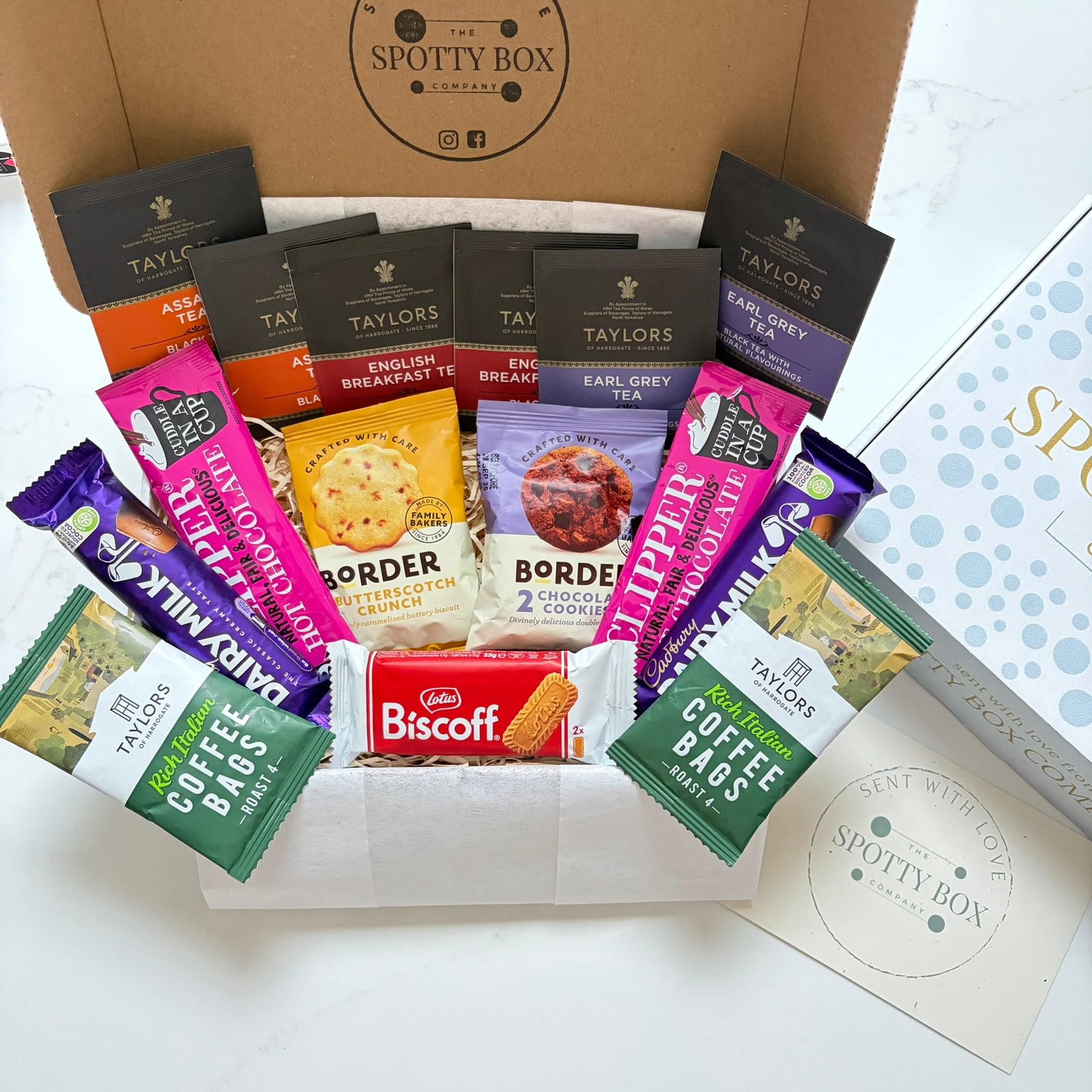 hot drink and biscuit gift hamper from the spotty box company containing taylors coffee sachets, taylors tea selection, border biscuits. cadbury dairy milk and clippers hot chocolate and a lotus biscoff biscuit. all presented in a tasteful 'spotty' box, ideal as a gift for tea and coffee lovers