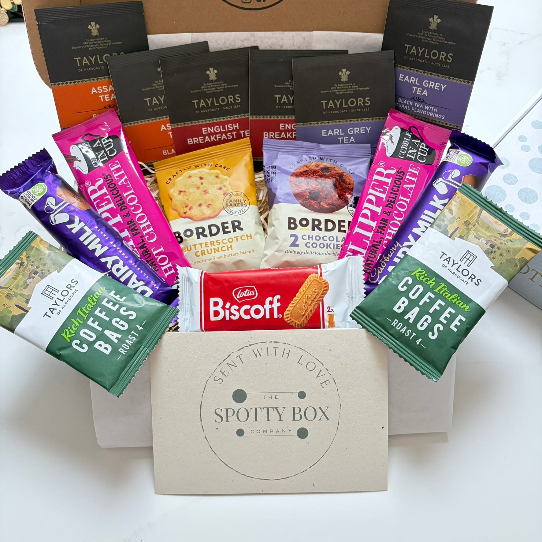 hot drink and biscuit gift hamper from the spotty box company containing taylors coffee sachets, taylors tea selection, border biscuits. cadbury dairy milk and clippers hot chocolate and a lotus biscoff biscuit. all presented in a tasteful 'spotty' box, ideal as a gift for tea and coffee lovers